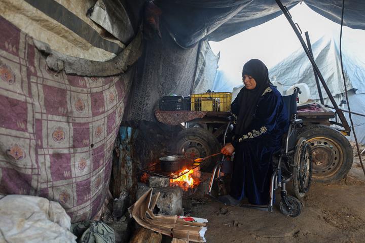 Maryam Abu Warda, de 44 años, amputada de un pie y un brazo tras un ataque de Israel en su casa, trata de cocinar en el campamento de Halawa (Gaza), el 14 de enero de 2026.