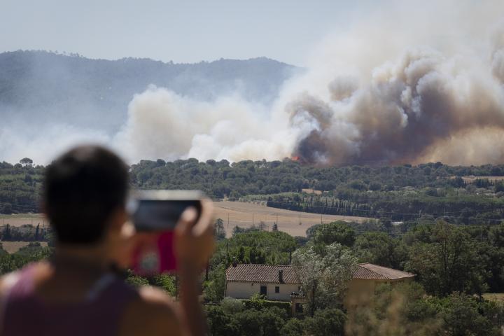 Un hombre observa la columna de humo del incendio forestal que se ha declarado en La Bisbal d'Empordà (Girona).