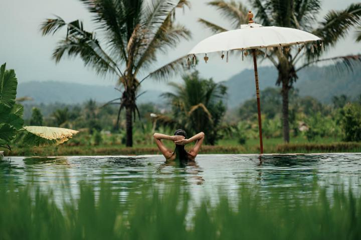 Una mujer dándose un baño en una piscina natural con vistas tropicales