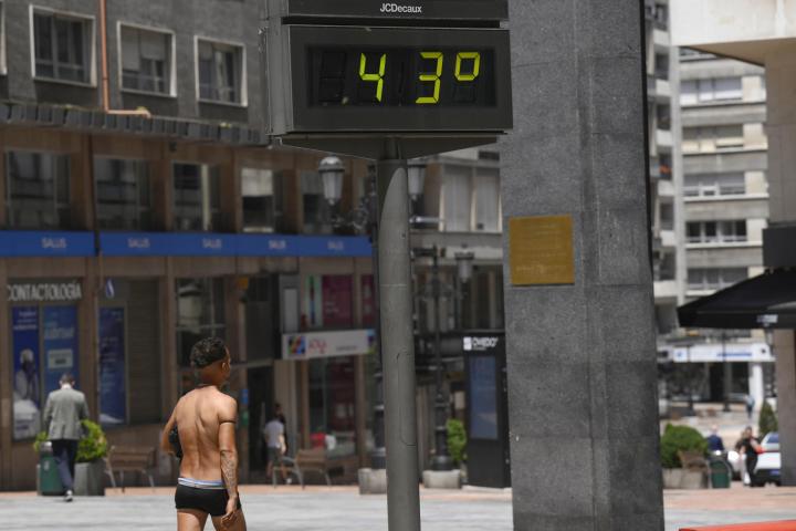 Un hombre semidesnudo pasea por el centro de Oviedo, en plena ola de calor.