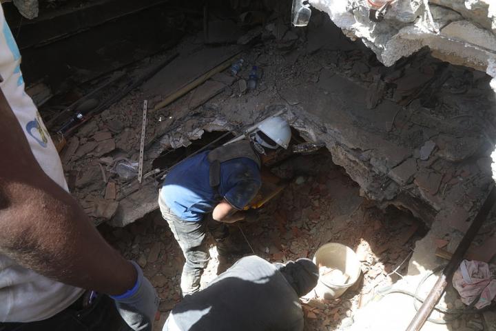 Un rescatista busca personas entre los escombros de un edificio afectado por los terremotos en La Guaira