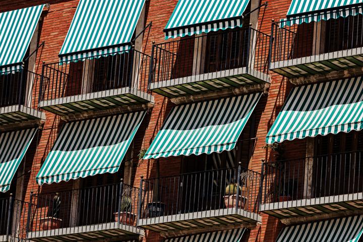 Varios toldos de franjas verdes y blancas sobre una serie de terrazas en un edificio