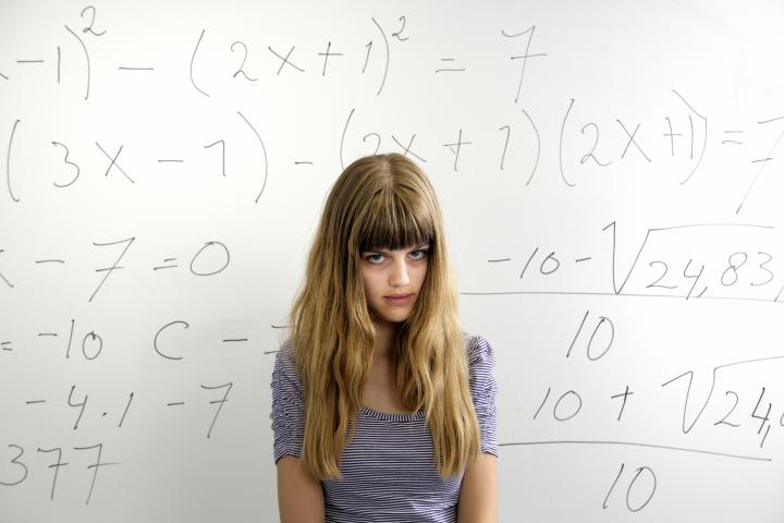 Una chica delante de una pizarra en una clase de un colegio