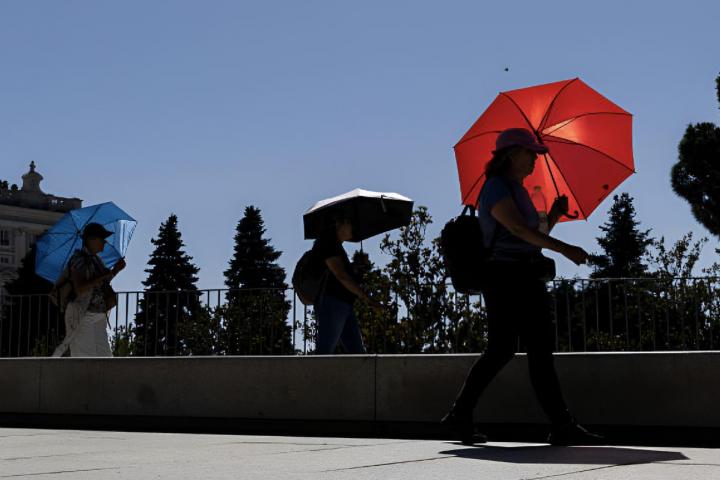 Varias personas protegiéndose del sol en Madrid