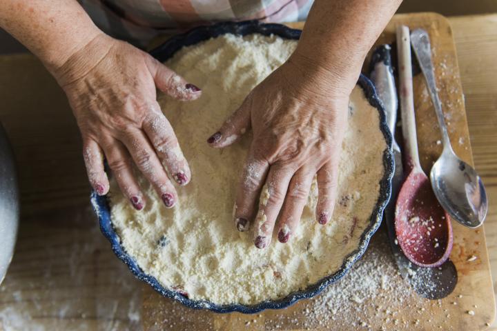 Mujer extendiendo la mezcla de crumble en un molde para pastel.