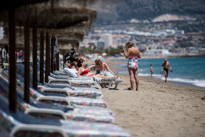 Unos extranjeros disfrutan del sol en la playa de Fuengirola (Málaga).