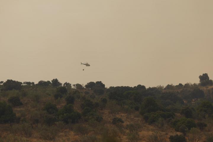 Un helicóptero del servicio de Bomberos trabaja en la extinción del incendio producido en la localidad madrileña de Pelayos de la Presa