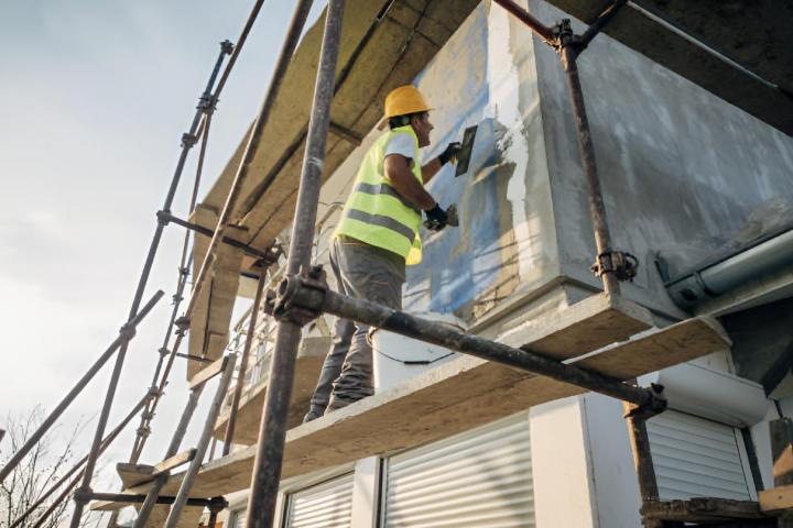 Un trabajador de la construcción construye la fachada de un edificio