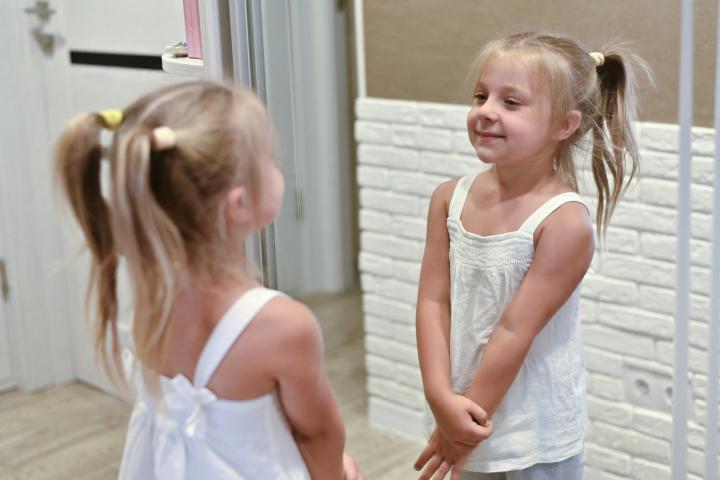 Una niña mirándose en un espejo, en una imagen de archivo