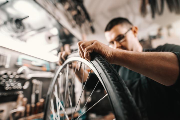 Un hombre repara la cámara de aire de una bicicleta.