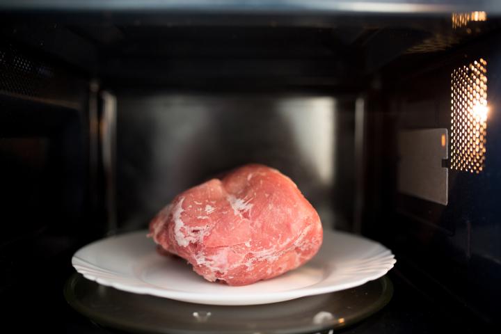Un trozo de carne descongelándose en el microondas.