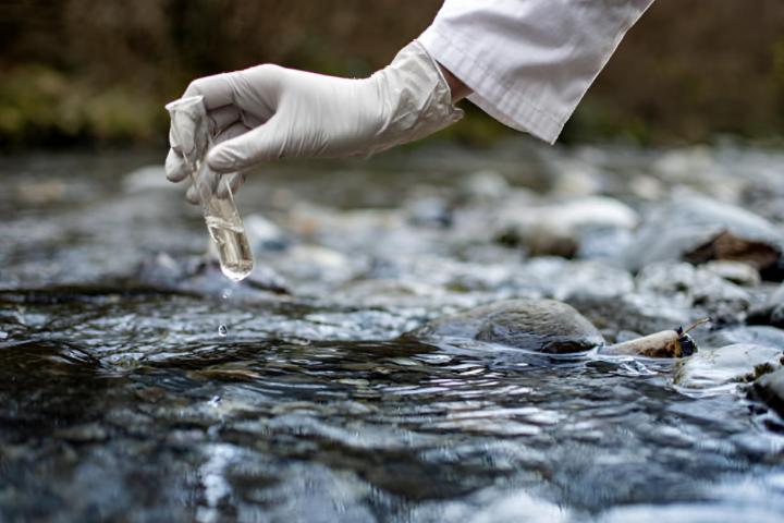 Un investigador recolecta una muestra de agua contaminada en un tubo de ensayo