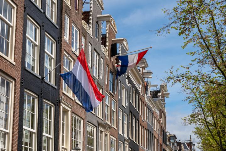 Esta es una foto de banderas holandesas en edificios de Ámsterdam, Países Bajos.