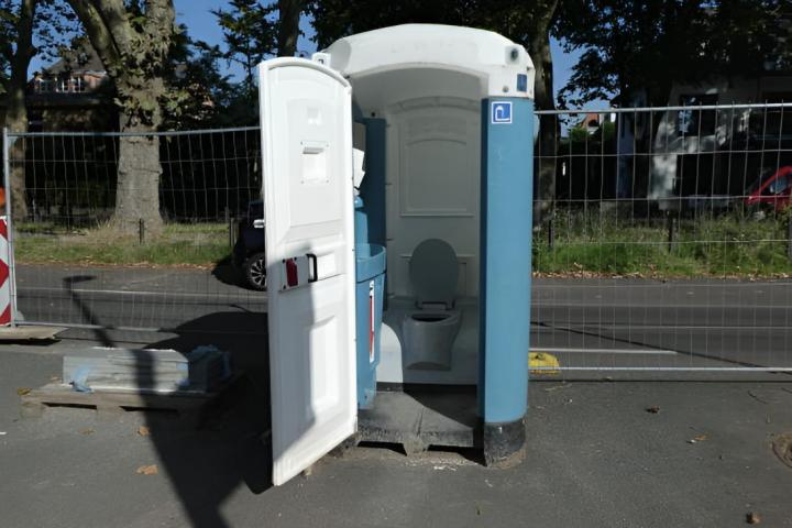 Un baño portátil, también llamado inodoro portátil, permanece abierto en una obra en construcción.