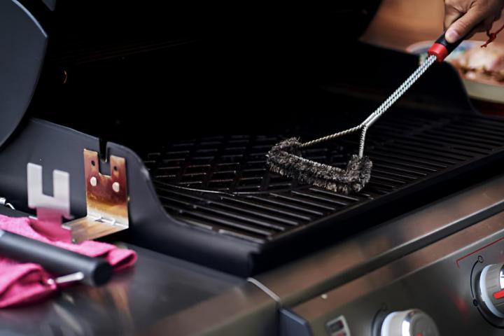 Un hombre limpiando la rejilla de la parrilla de la barbacoa