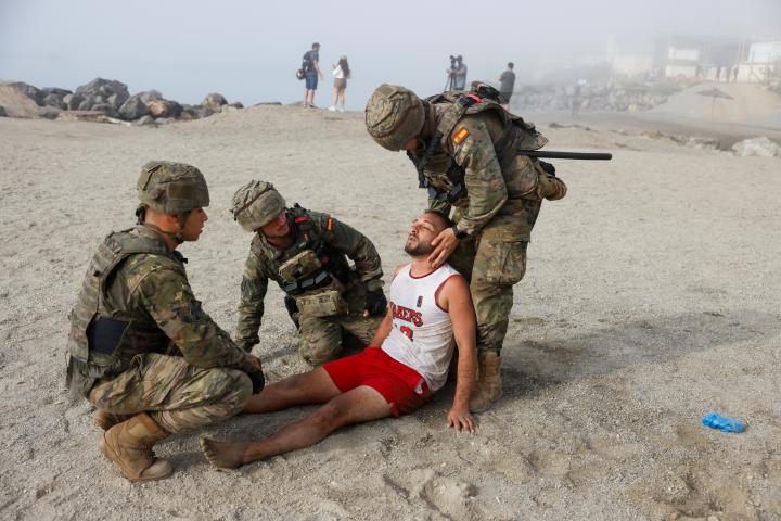 Soldados españoles rescatan a un migrante herido en la playa, tras la llegada masiva a pie y por mar desde Marruecos, en Ceuta, el 1 de agosto de 2026.