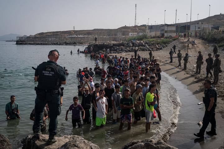 Un grupo de personas espera instrucciones de la Guardia Civil en la playa de Tarajal, tras cruzar la frontera entre España y Marruecos, el 31 de julio de 2026.