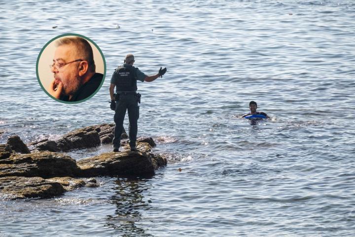 Un guardia civil espera en las rocas del Tarajal a un migrante marroquí en Ceuta