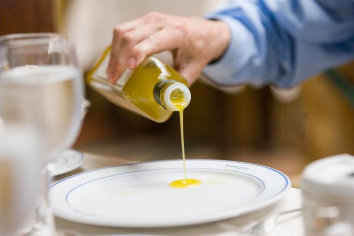 Un hombre echa aceite a su plato en un restaurante