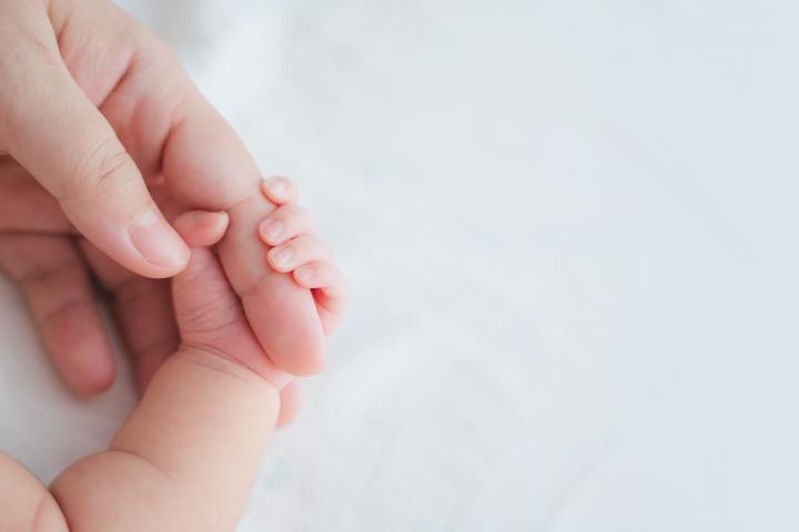 Una madre le sujeta la mano a un bebé recién nacido