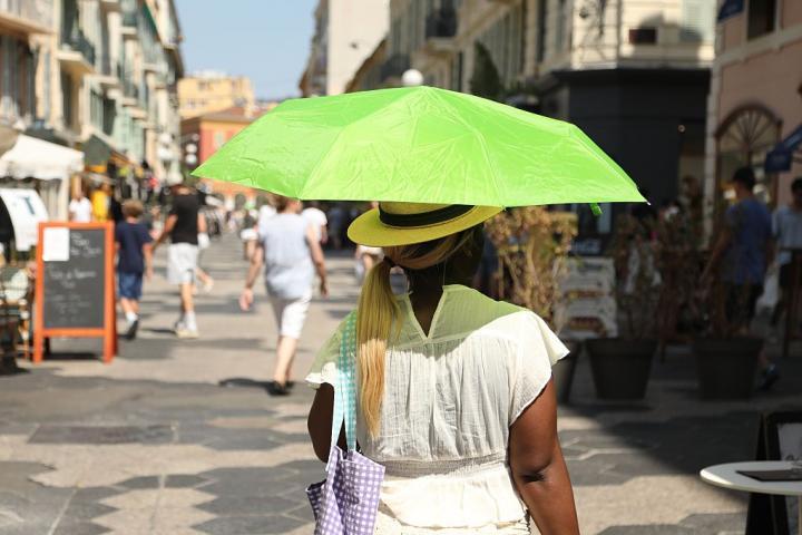 Una mujer se protege con una sombrilla del calor extremo en Niza en mitad de julio