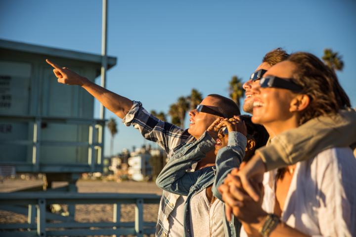 Un grupo de chicos observa un eclipse desde la playa.