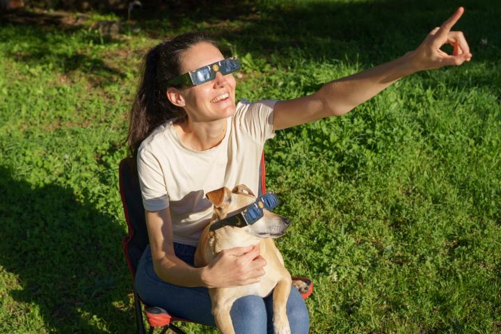 Una mujer y su perro con gafas de eclipse