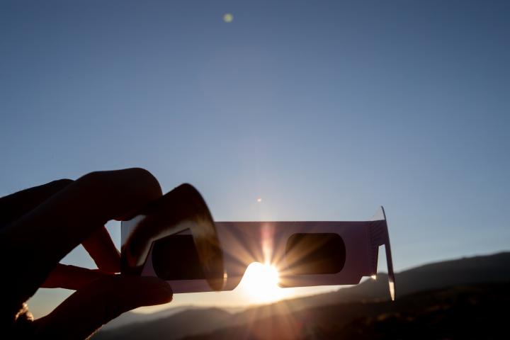 Una persona sosteniendo unas gafas para ver protegerse de la luz solar.