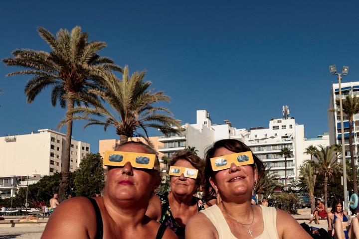 Un grupo de turistas de Colonia (Alemania), con sus gafas protectoras antes del eclipse solar en la playa de El Arenal (Mallorca), el 12 de agosto de 2026.