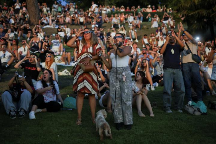 Varias personas utilizan gafas protectoras y hacen fotos del eclipse desde el Templo de Debod, cerca del Palacio Real de Madrid, el 12 de agosto de 2026.
