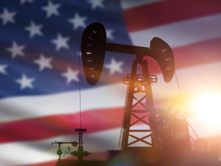 Ilustración de una planta petrolera, con la bandera de EEUU al fondo.