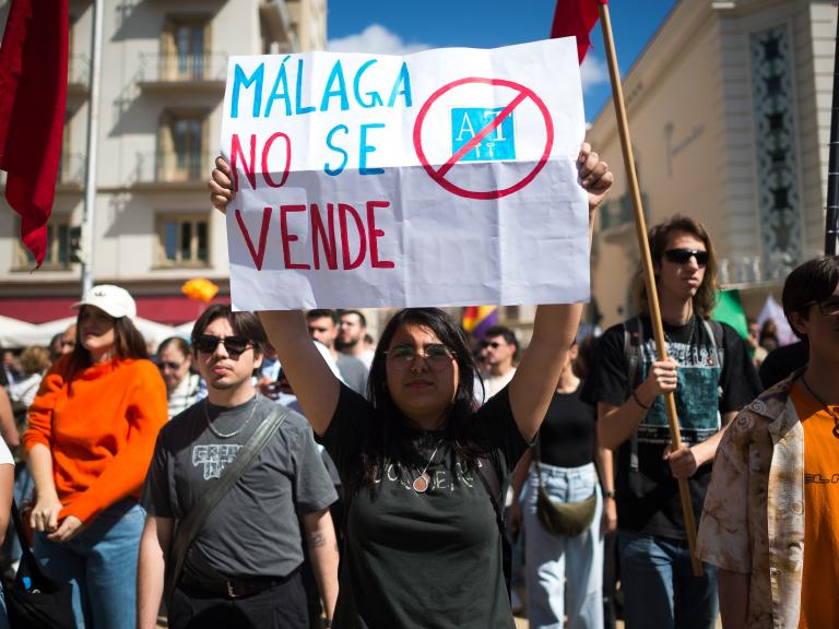 Una mujer sostiene un cartel en la manifestación de abril de 2025 en Málaga por la vivienda, en él se lee: "Málaga no se vende"