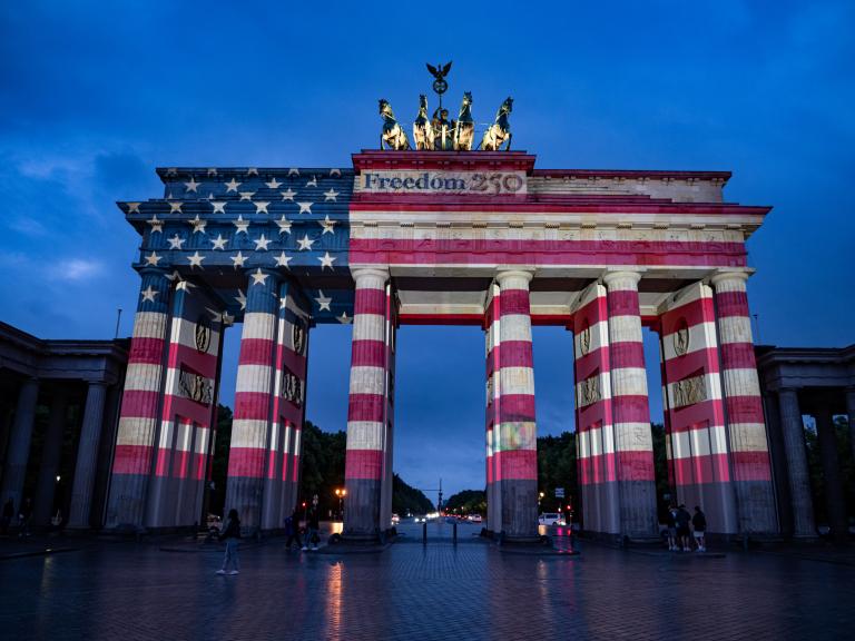 La gente contempla la Puerta de Brandeburgo, iluminada con los colores de los Estados Unidos de América para conmemorar el 250 aniversario de la independencia estadounidense.