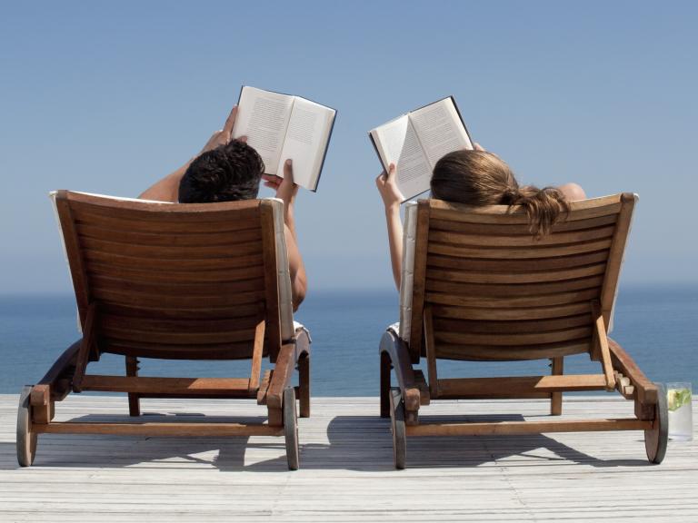 Una pareja leyendo libros durante sus vacaciones de verano