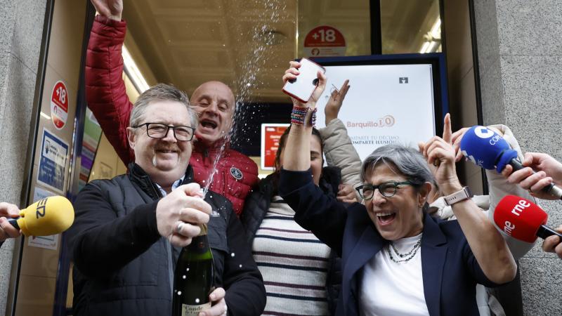 Varias personas celebran a las puertas de la administración de loterías del número 10 de la calle Barquillo, en Madrid, donde se ha vendido íntegramente el 70.048, el segundo premio del Sorteo Extraordinario de la Lotería de Navidad.