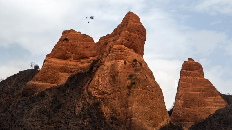 Imagen de un helicóptero de extinción sobrevolando el parque natural de Las Médulas (León), calcinado por los incendios del verano de 2025.